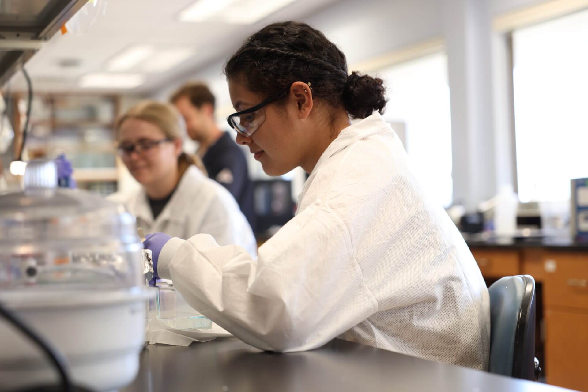 SHINE Student in lab coat in Prof. McCain's lab
